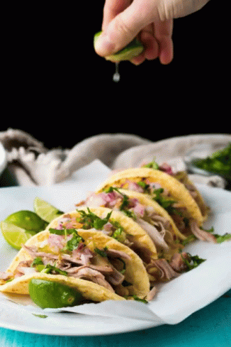 A Person Is Squeezing A Lime Over A Stack Of Tacos GIF