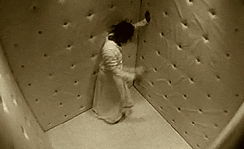 A Person Is Standing In A Corner Of A Room With Holes In The Walls . GIF