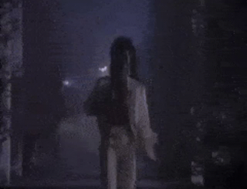 A Person Is Standing In A Dark Room With A Purple Background . GIF