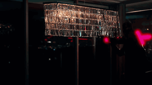 A Person Is Standing In A Dark Room With A Red Light Behind Them GIF