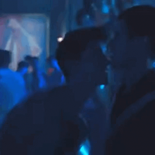 A Person Is Standing In A Dark Room With Blue Lights Behind Them GIF