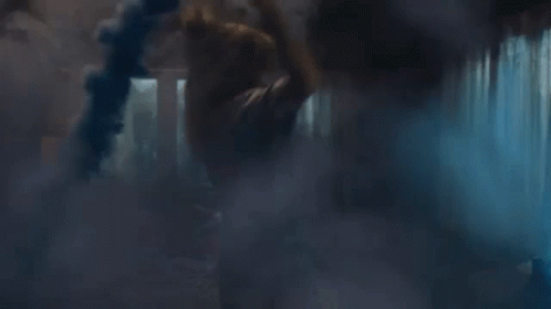 A Person Is Standing In A Dark Room With Smoke Coming Out Of The Window . GIF