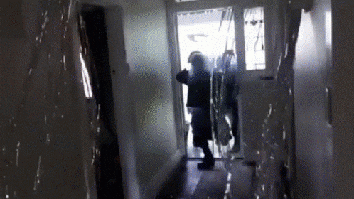 A Person Is Standing In A Hallway With A Door Open GIF