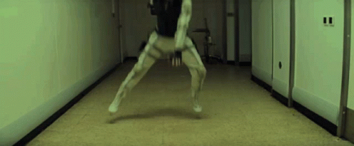 A Person Is Standing In A Hallway With Their Legs Crossed . GIF