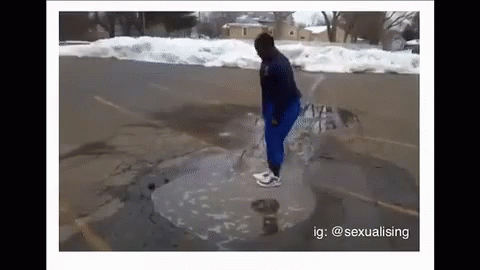 A Person Is Standing In A Puddle Of Water On The Side Of A Road . GIF