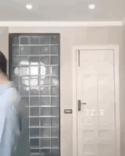 A Person Is Standing In A Room With A Door And A Window . GIF