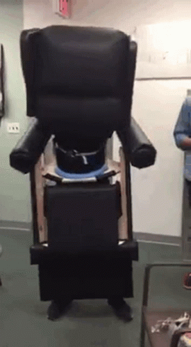 A Person Is Standing In Front Of A Chair That Looks Like A Giant Chair GIF