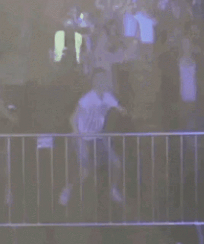 A Person Is Standing In Front Of A Fence With A Fireball Coming Out Of The Fence . GIF