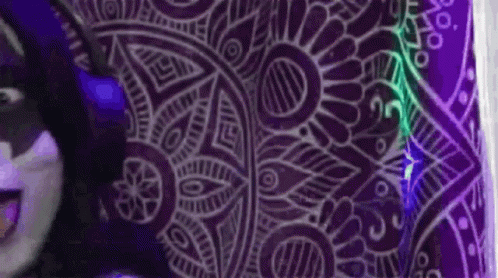 A Person Is Standing In Front Of A Purple Wall With A Purple Pattern On It . GIF