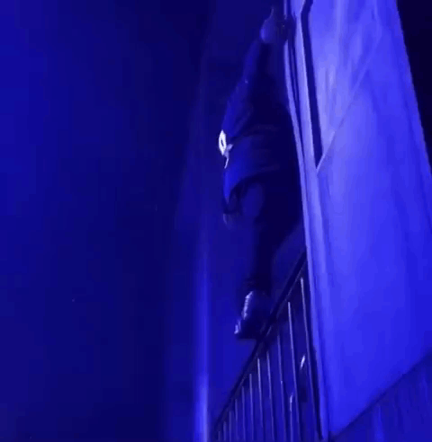 A Person Is Standing On A Balcony In A Dark Room With Blue Lights . GIF