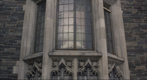A Person Is Standing On A Balcony With A Stained Glass Window GIF