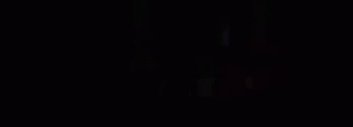 A Person Is Standing On A Bed In A Dark Room With Smoke Coming Out Of The Window . GIF