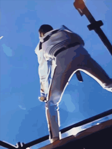A Person Is Standing On A Railing With A Blue Sky Behind Them GIF