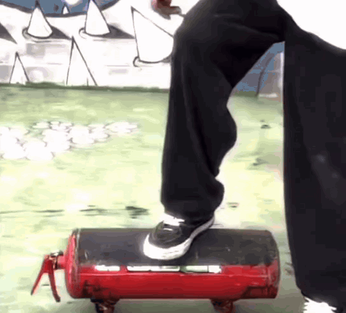 A Person Is Standing On A Red Fire Extinguisher With Wheels GIF