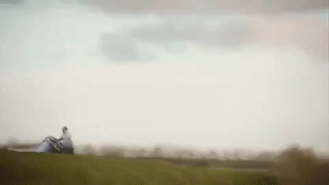 A Person Is Standing On Top Of A Grassy Hill Holding A Large Piece Of Paper . GIF