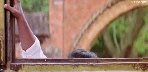 A Person Is Sticking Their Head Out Of A Window With A Brick Wall In The Background . GIF