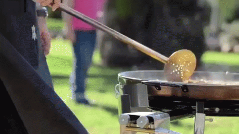 A Person Is Stirring Food In A Pan With A Wooden Ladle GIF