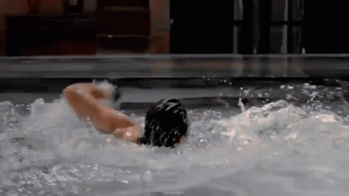 A Person Is Swimming In A Pool With A Blurred Background GIF