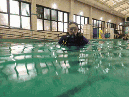 A Person Is Swimming In A Pool With A Scuba Diving Mask On GIF