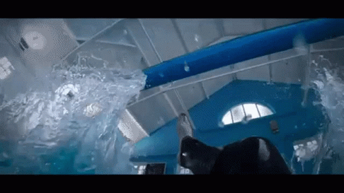 A Person Is Swimming In A Pool With A Water Slide . GIF