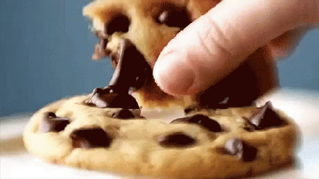 A Person Is Taking A Bite Out Of A Chocolate Chip Cookie GIF