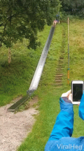 A Person Is Taking A Picture Of A Slide With A Cell Phone With Viralhog Written On It GIF