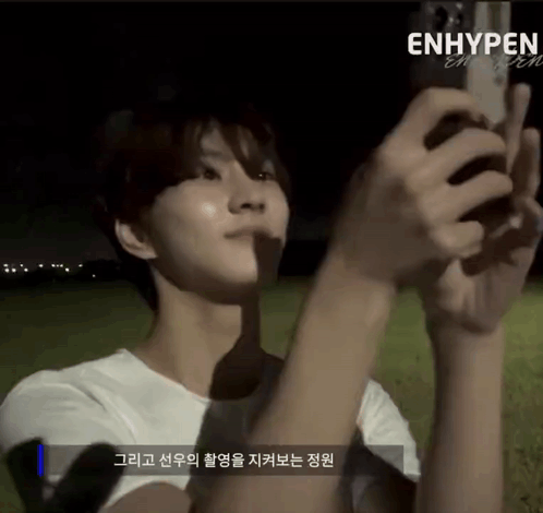 A Person Is Taking A Picture With A Cell Phone And The Word Enhypen Is On The Bottom GIF