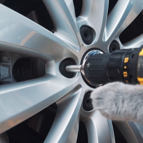 A Person Is Using A Drill To Remove A Screw From A Wheel GIF