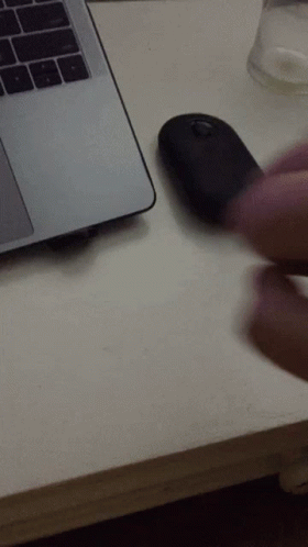 A Person Is Using A Mouse Next To A Laptop Computer GIF