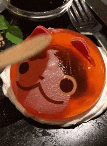 A Person Is Using A Wooden Spoon To Spread Jelly With A Cat Face On It GIF