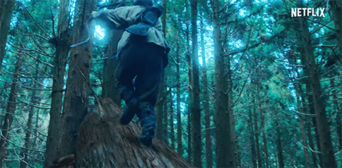 A Person Is Walking Through A Forest With A Backpack And A Light On Their Back . GIF