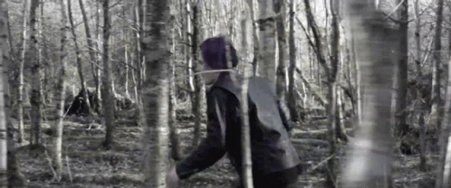 A Person Is Walking Through A Forest With A Rope Around Their Neck . GIF