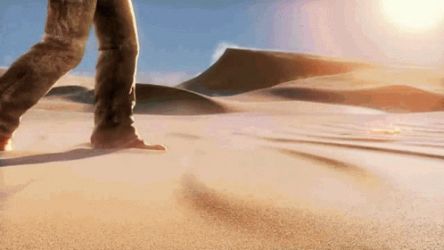 A Person Is Walking Through A Sandy Desert Landscape GIF