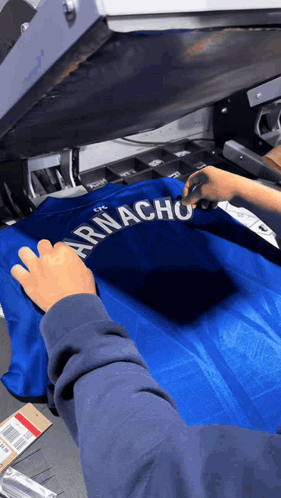 a person is working on a shirt that says armacho on it