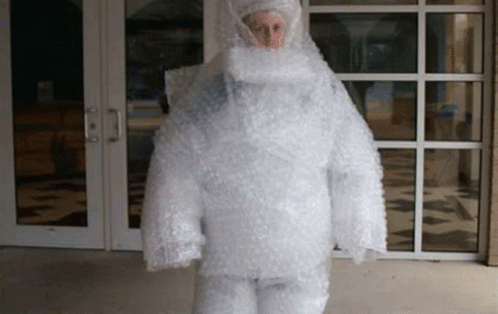A Person Is Wrapped In Bubble Wrap And Is Standing In Front Of A Building . GIF