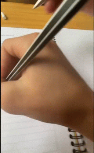 A Person Is Writing On A Notebook With A Pencil GIF