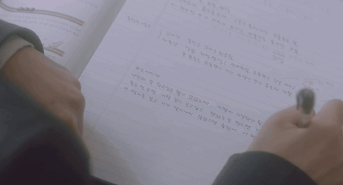 A Person Is Writing On A Piece Of Paper With A Pen GIF