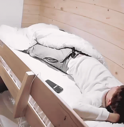 A Person Laying In A Bunk Bed With A Remote Control On The Side GIF