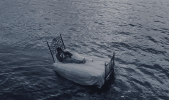 A Person Laying On A Bed In The Middle Of The Ocean GIF