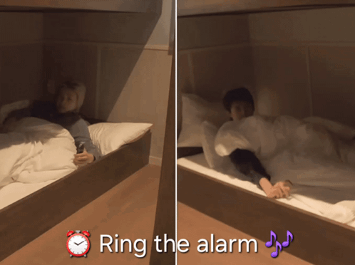 A Person Laying On A Bed Next To An Alarm Clock That Says " Ring The Alarm " On It GIF