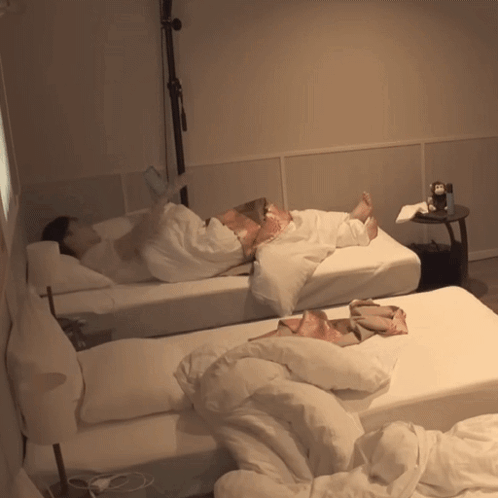 A Person Laying On A Bed Next To Another Person GIF