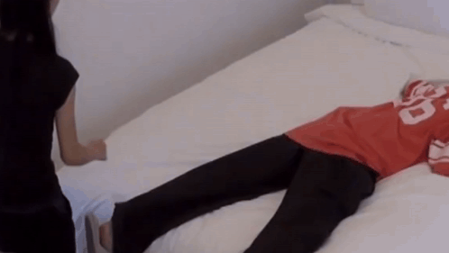 A Person Laying On A Bed Wearing A Red Shirt With The Number 20 On It GIF