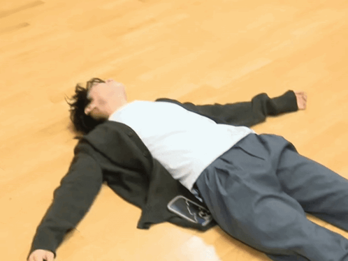 A Person Laying On A Wooden Floor With A Cell Phone In Their Pocket GIF