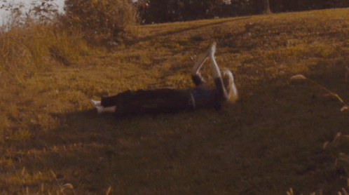 A Person Laying On The Grass With Their Feet In The Air GIF