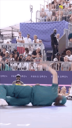 A Person Laying On The Ground In Front Of A Sign That Says " Paris 2024 " GIF