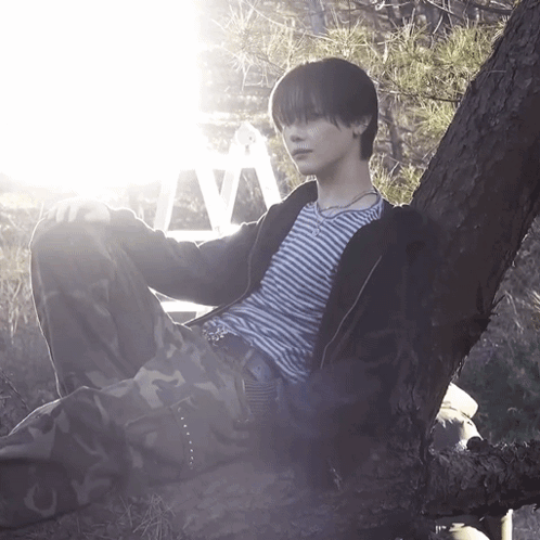 A Person Leaning Against A Tree With The Letter V Visible Behind Them GIF
