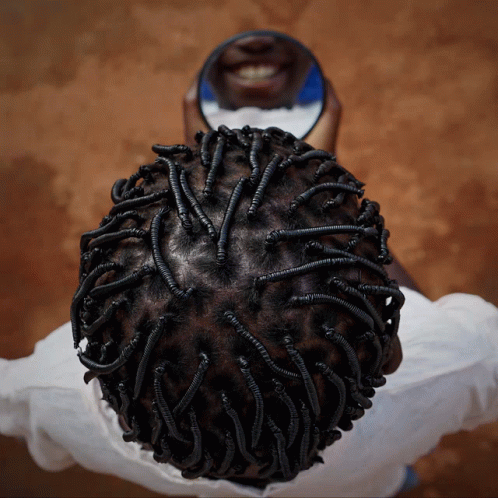 A Person Looking At Their Hair In A Mirror And Smiling GIF