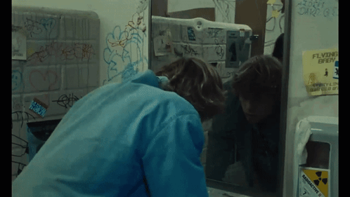 A Person Looking At Their Reflection In A Bathroom Mirror GIF