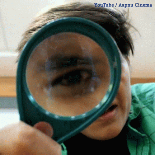 A Person Looking Through A Magnifying Glass With Youtube / Aapnu Cinema Written On The Bottom GIF