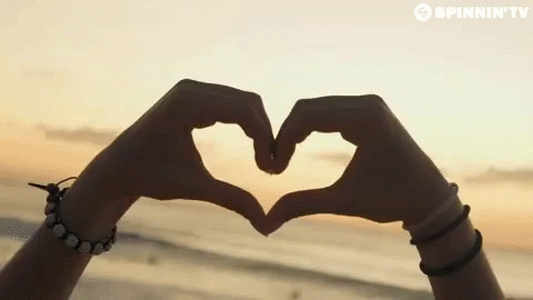 A Person Making A Heart Shape With Their Hands In Front Of A Spinnin ' Tv Banner GIF